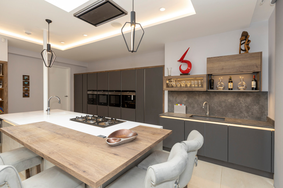 Photo of a large modern l-shaped eat-in kitchen in Hertfordshire with a single-bowl sink, flat-panel cabinets, grey cabinets, quartzite benchtops, grey splashback, cement tile splashback, black appliances, porcelain floors, with island, white floor, grey benchtop and recessed.