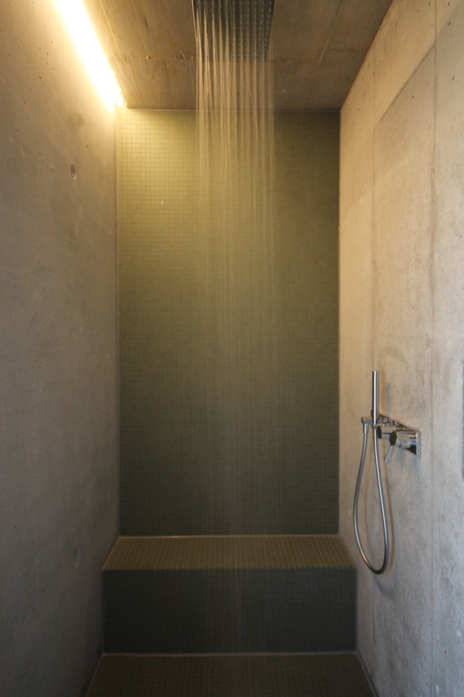 Mid-sized modern 3/4 bathroom in Stuttgart with flat-panel cabinets, medium wood cabinets, a drop-in tub, a curbless shower, green tile, mosaic tile, grey walls, concrete floors, an integrated sink and concrete benchtops.