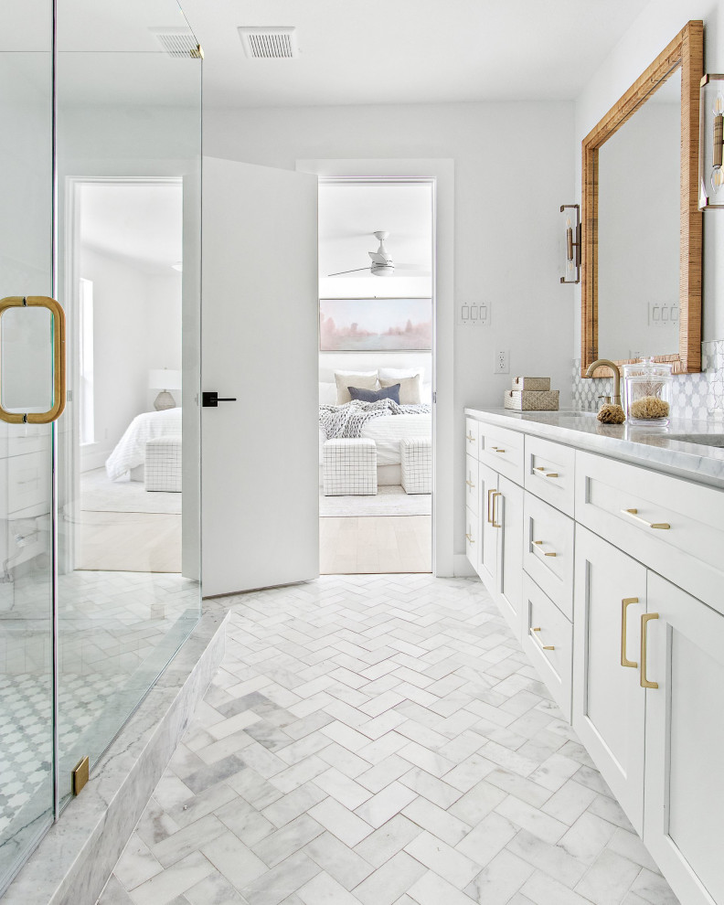 Inspiration for a large beach style ensuite bathroom in Dallas with shaker cabinets, white cabinets, light hardwood flooring, a corner shower, white tiles, metro tiles, white walls, a submerged sink, marble worktops, white floors, a hinged door, white worktops, double sinks and a built in vanity unit.
