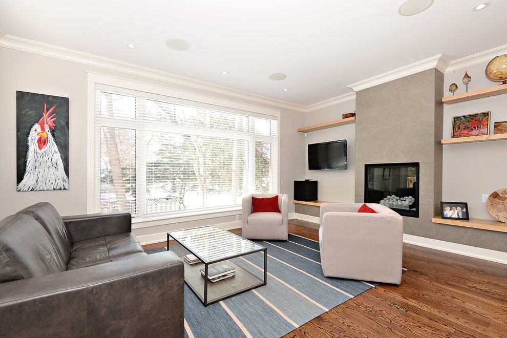 This is an example of a mid-sized transitional formal enclosed living room in Ottawa with grey walls, medium hardwood floors, a ribbon fireplace and a wall-mounted tv.