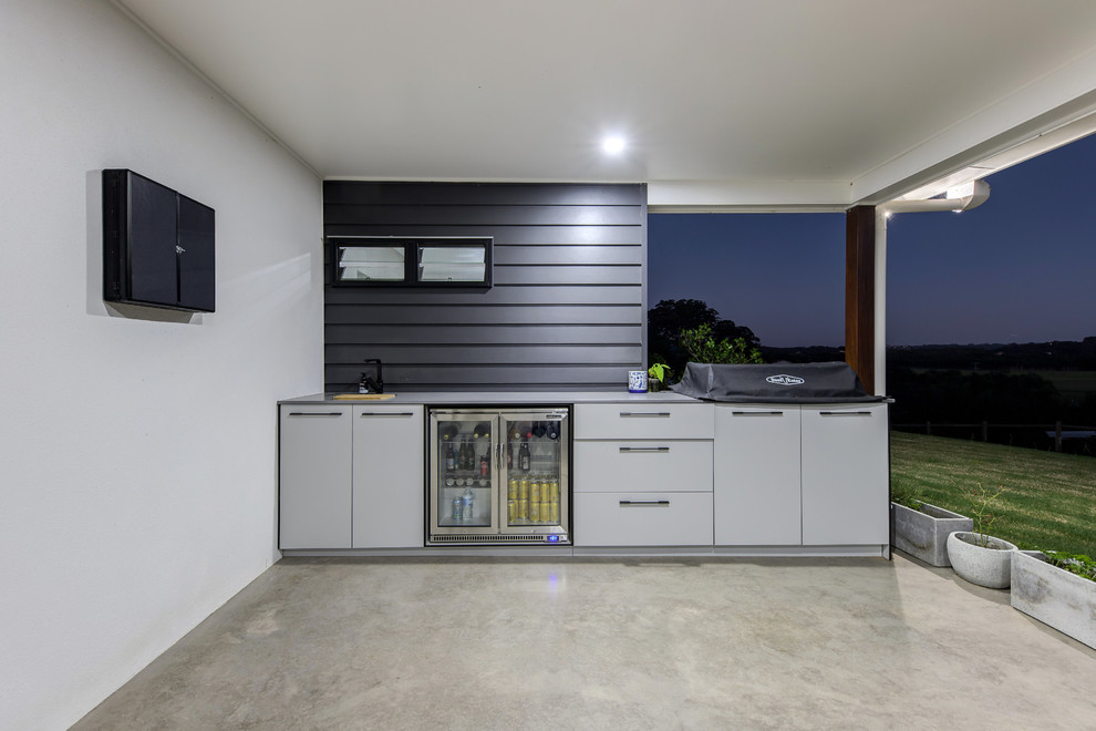 Large industrial backyard patio in Sunshine Coast with an outdoor kitchen, concrete slab and a roof extension.