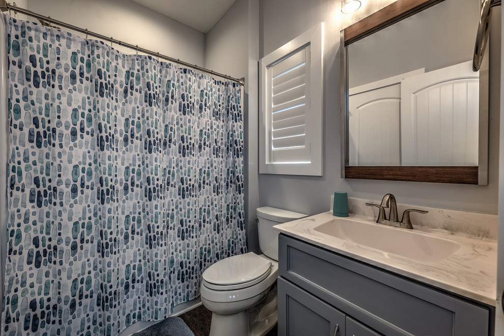 Design ideas for a small arts and crafts bathroom in Atlanta with shaker cabinets, grey cabinets, an alcove tub, a two-piece toilet, grey walls, vinyl floors, an undermount sink, marble benchtops, a shower curtain, white benchtops, a single vanity, a built-in vanity, a shower/bathtub combo and brown floor.