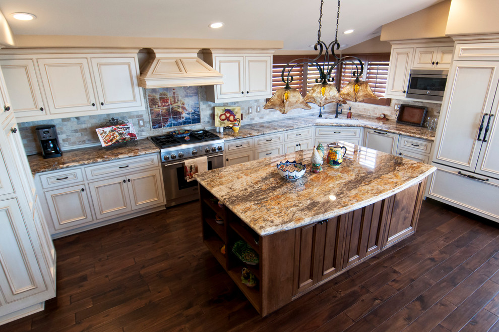 Design ideas for a large traditional u-shaped eat-in kitchen in Orange County with an undermount sink, raised-panel cabinets, white cabinets, granite benchtops, beige splashback, stone tile splashback, stainless steel appliances, dark hardwood floors and with island.