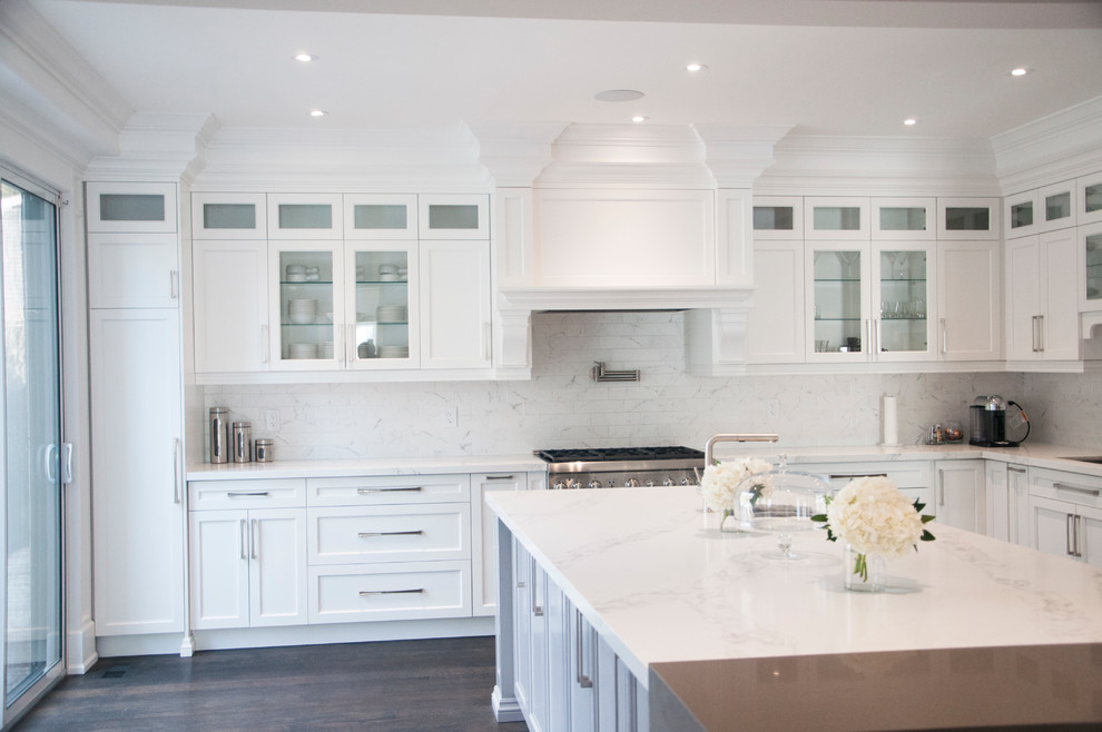 Example of a large transitional l-shaped dark wood floor and brown floor enclosed kitchen design in Toronto with an undermount sink, shaker cabinets, white cabinets, quartz countertops, white backsplash, marble backsplash, stainless steel appliances, an island and white countertops