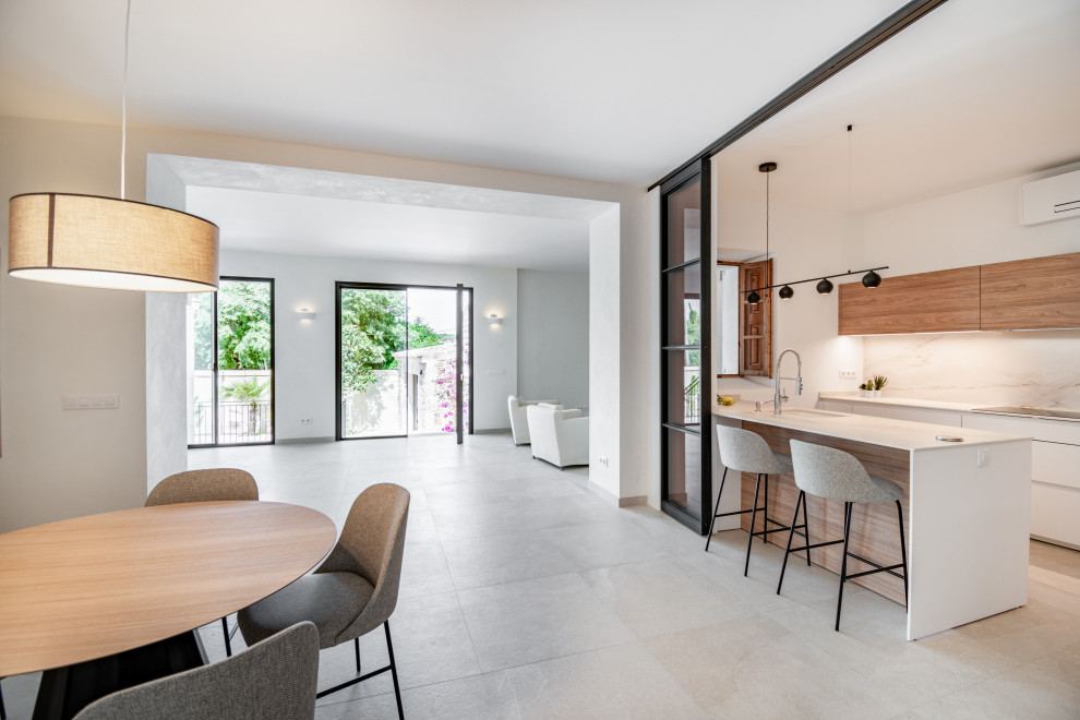 Design ideas for a large contemporary l-shaped open plan kitchen in Palma de Mallorca with a submerged sink, flat-panel cabinets, white cabinets, white splashback, a breakfast bar and white worktops.