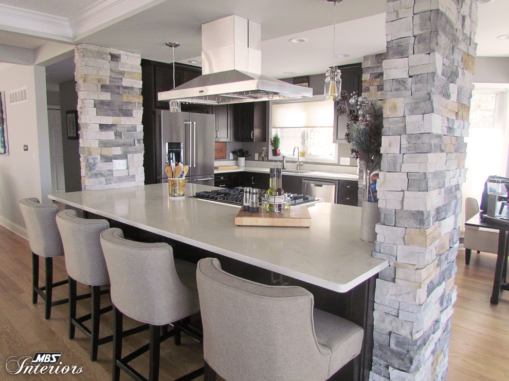 Eat-in kitchen - large transitional l-shaped light wood floor eat-in kitchen idea with an undermount sink, recessed-panel cabinets, dark wood cabinets, quartz countertops, stainless steel appliances and an island