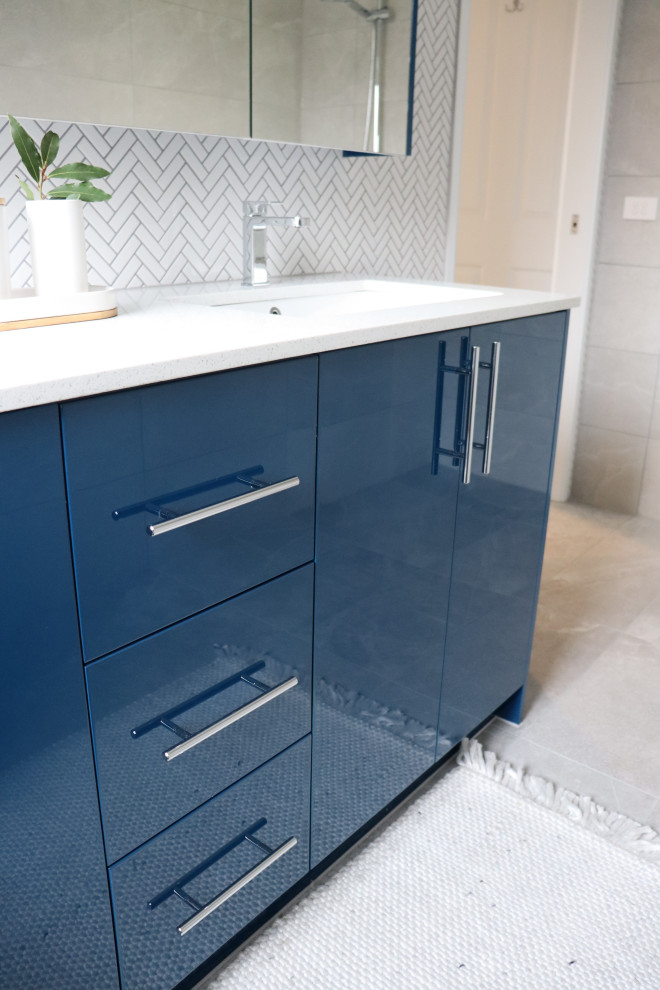 Inspiration for a medium sized contemporary ensuite bathroom in Melbourne with flat-panel cabinets, blue cabinets, a walk-in shower, grey tiles, ceramic tiles, engineered stone worktops, an open shower, white worktops, double sinks and a built in vanity unit.