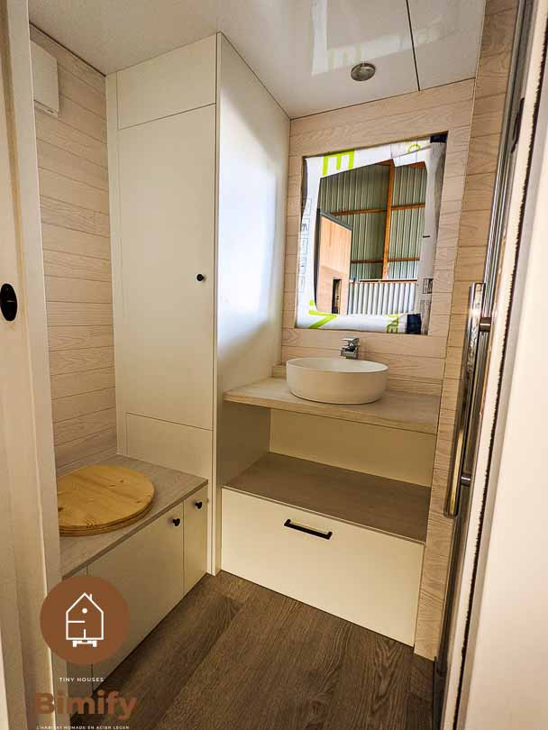 Photo of a small modern 3/4 bathroom in Bordeaux with recessed-panel cabinets, white cabinets, a curbless shower, a one-piece toilet, white walls, laminate floors, a drop-in sink, laminate benchtops, brown floor, a hinged shower door, beige benchtops, a single vanity, a built-in vanity, coffered and planked wall panelling.