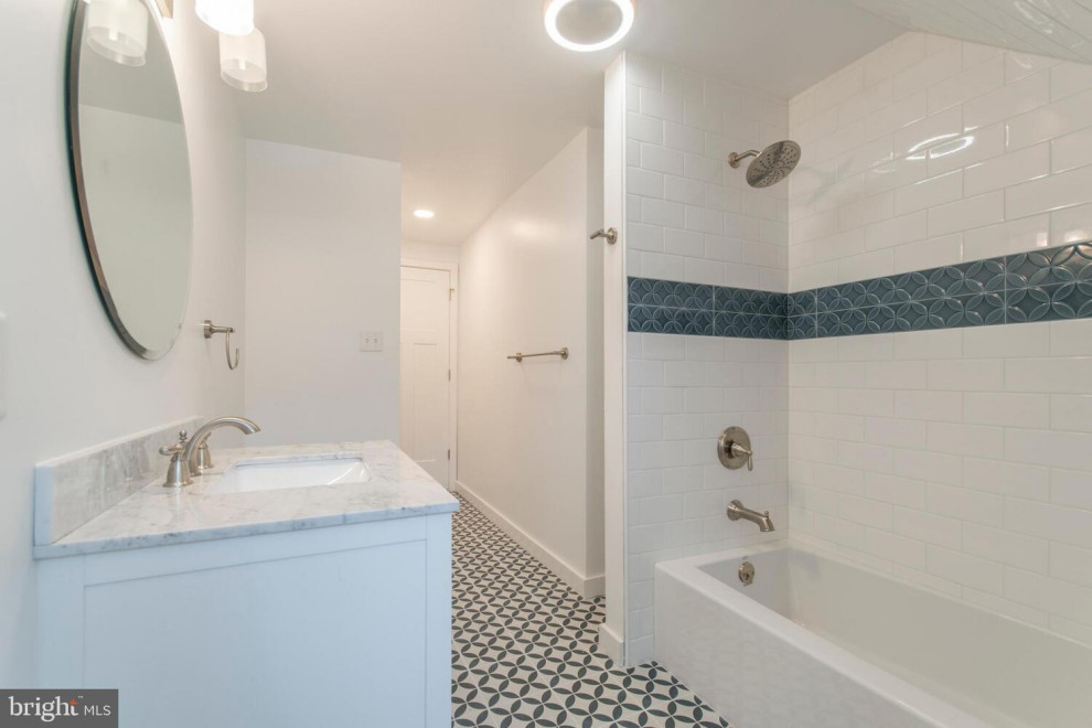 Idéer för att renovera ett lantligt grå grått badrum för barn, med vita skåp, ett badkar i en alkov, en dusch/badkar-kombination, en toalettstol med hel cisternkåpa, vit kakel, tunnelbanekakel, vita väggar, klinkergolv i keramik, ett undermonterad handfat, marmorbänkskiva, blått golv och med dusch som är öppen