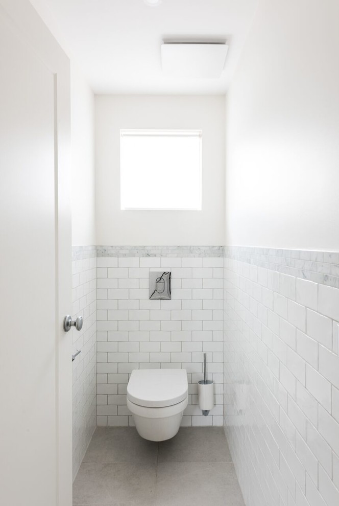 This is an example of a small traditional master bathroom with shaker cabinets, white cabinets, a wall-mount toilet, white tile, marble, white walls, porcelain floors and grey floor.
