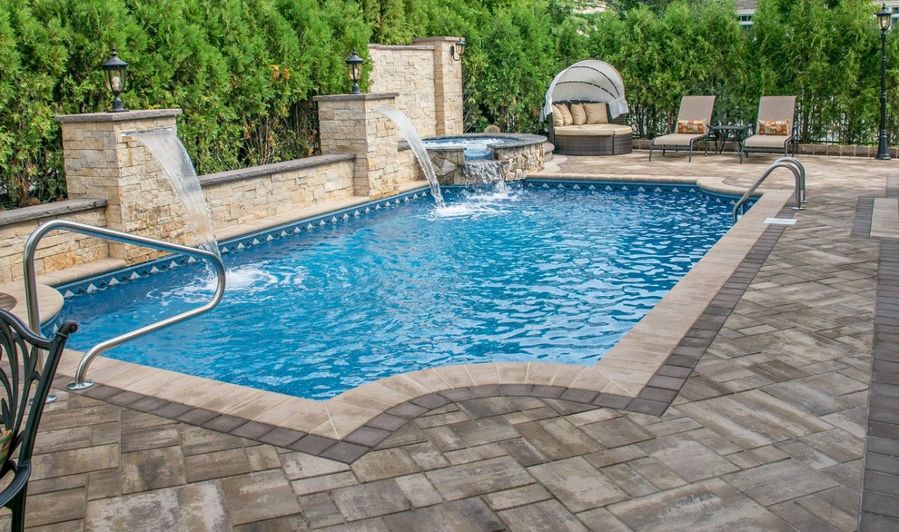 Photo of a large traditional backyard rectangular lap pool in New York with a water feature and concrete pavers.