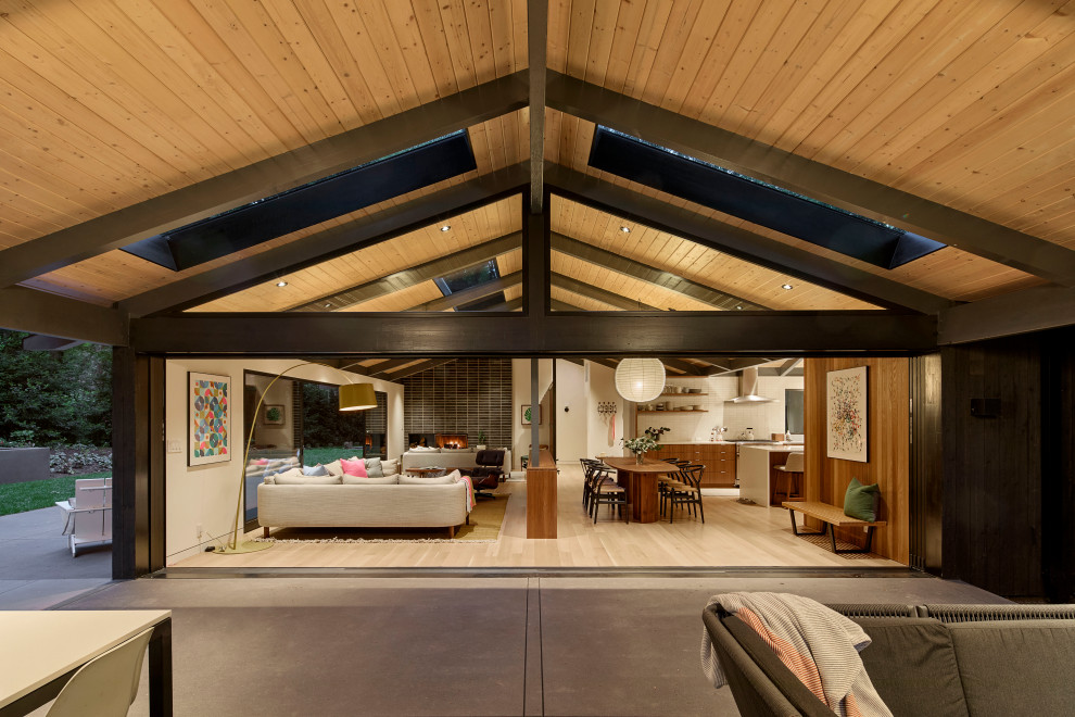 Cette image montre une grande terrasse latérale vintage avec un foyer extérieur, une dalle de béton et une extension de toiture.