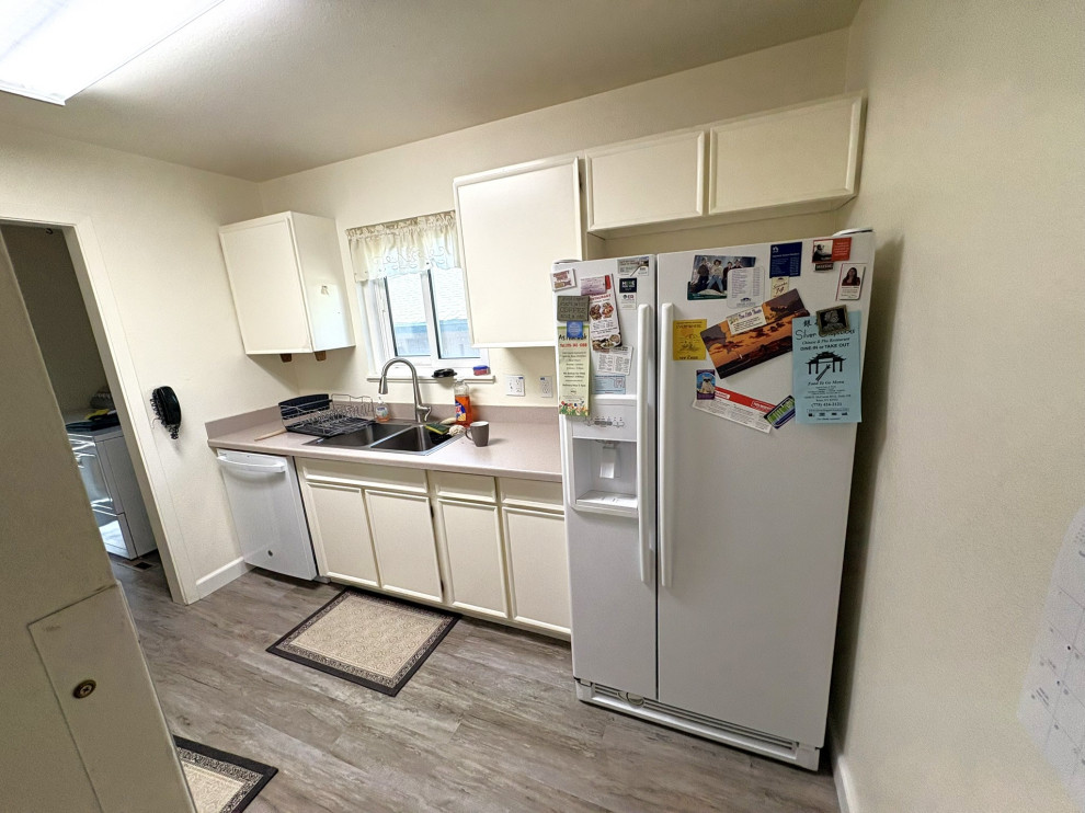 Example of a small transitional vinyl floor and brown floor enclosed kitchen design with an undermount sink, shaker cabinets, white cabinets, quartzite countertops, blue backsplash, mosaic tile backsplash, white appliances, an island and white countertops