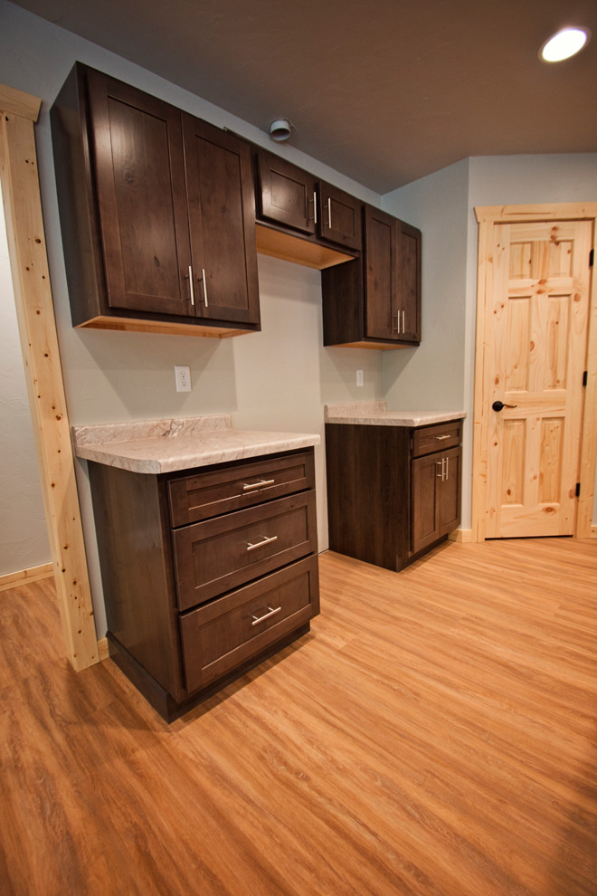 Example of a mid-sized mountain style l-shaped medium tone wood floor and brown floor eat-in kitchen design with a double-bowl sink, recessed-panel cabinets, dark wood cabinets, an island and gray countertops