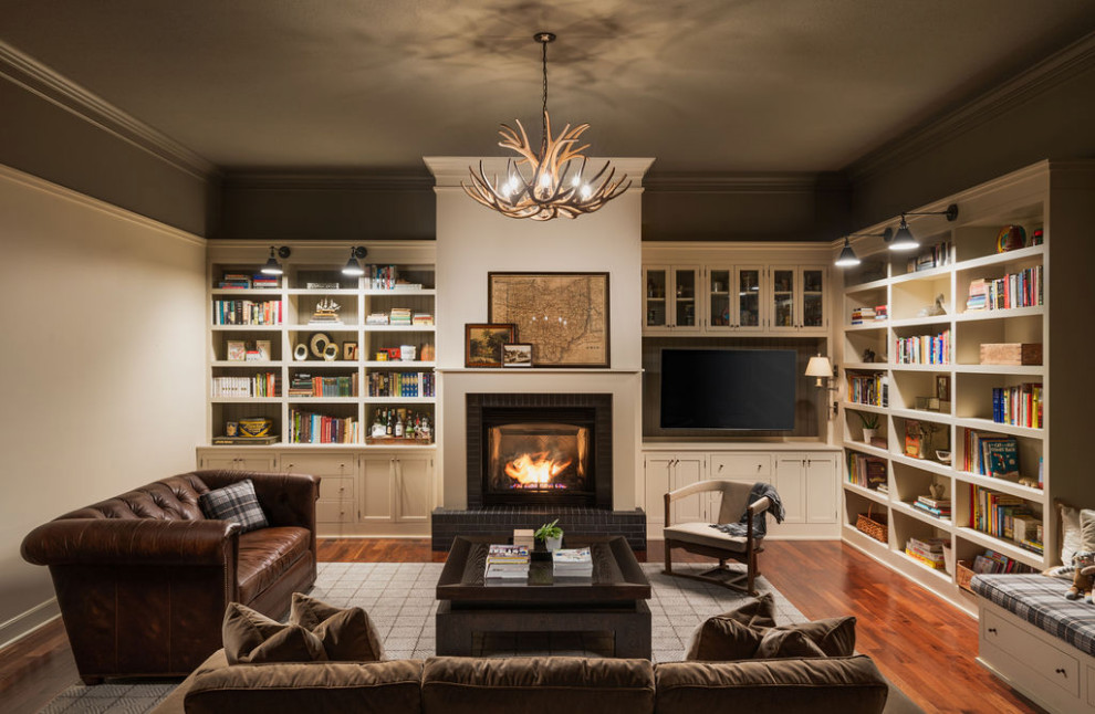 Idées déco pour une grande salle de séjour classique avec une bibliothèque ou un coin lecture, un sol en bois brun, une cheminée standard, un manteau de cheminée en brique, un téléviseur encastré et un sol marron.