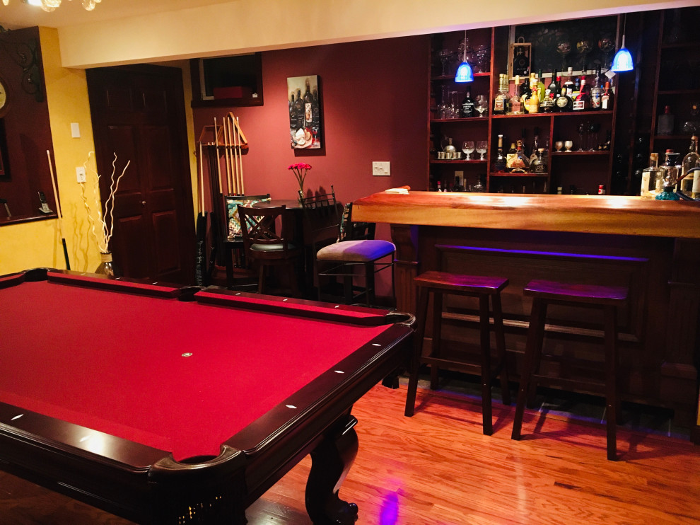 Mid-sized elegant walk-out medium tone wood floor and brown floor basement game room photo in Philadelphia with red walls