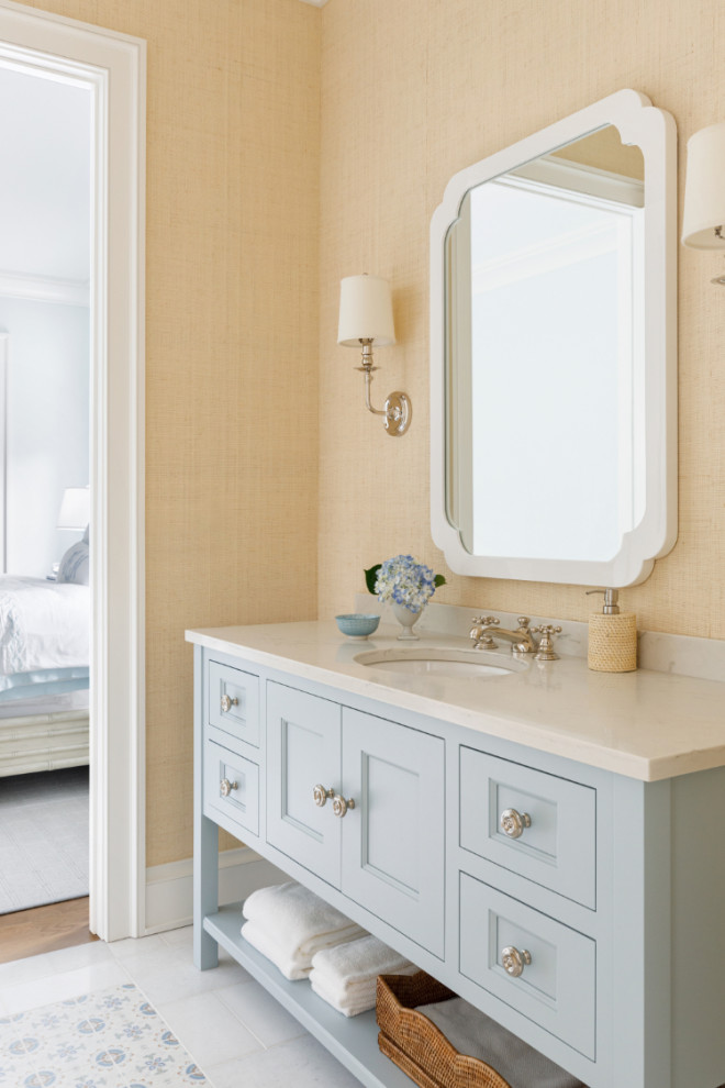 Photo of a mid-sized beach style 3/4 bathroom in Milwaukee with recessed-panel cabinets, blue cabinets, yellow walls, ceramic floors, an undermount sink, quartzite benchtops, multi-coloured floor, beige benchtops, a single vanity, a freestanding vanity and wallpaper.