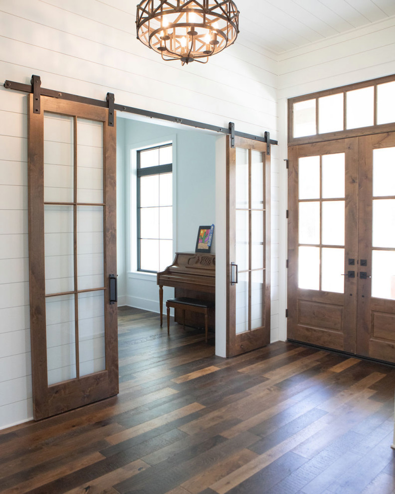Cette photo montre un grand hall d'entrée nature avec un mur blanc, un sol en bois brun, une porte double, une porte en bois brun, un sol marron, un plafond en lambris de bois et du lambris de bois.
