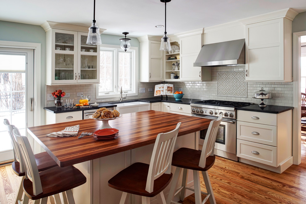 Inspiration for a mid-sized country u-shaped separate kitchen in Chicago with a farmhouse sink, shaker cabinets, white cabinets, granite benchtops, white splashback, subway tile splashback, stainless steel appliances and medium hardwood floors.