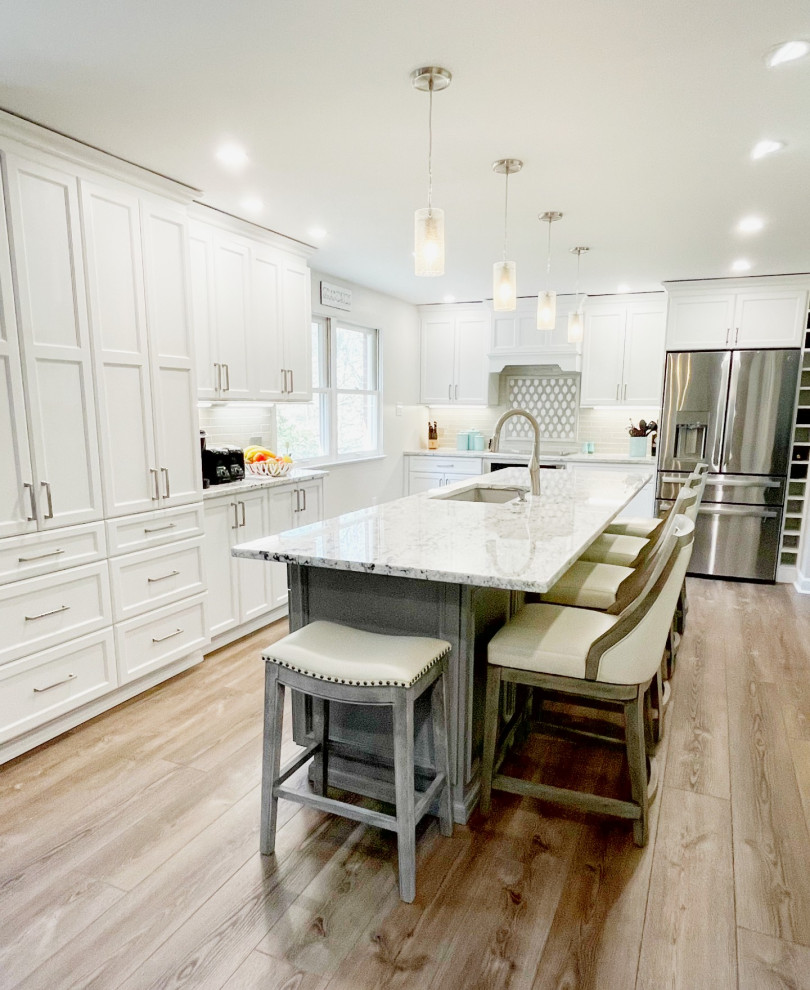 Example of a mid-sized transitional kitchen design with an undermount sink, recessed-panel cabinets, white cabinets, granite countertops, gray backsplash, stainless steel appliances and white countertops