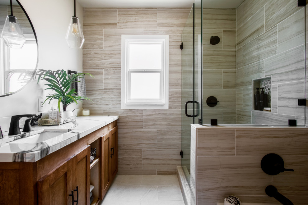 На фото: ванная комната среднего размера в стиле неоклассика (современная классика) с фасадами цвета дерева среднего тона, ванной в нише, угловым душем, разноцветной плиткой, керамогранитной плиткой, бежевыми стенами, полом из керамогранита, врезной раковиной, столешницей из гранита, бежевым полом, душем с распашными дверями, разноцветной столешницей, тумбой под одну раковину, напольной тумбой и фасадами в стиле шейкер