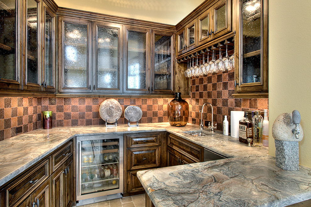 Photo of a small mediterranean u-shaped wet bar in Austin with an undermount sink, glass-front cabinets, dark wood cabinets, granite benchtops, brown splashback and limestone floors.