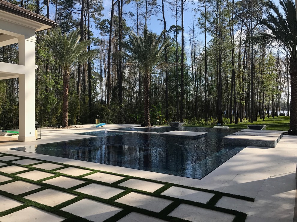 Photo of an expansive modern backyard custom-shaped infinity pool in Orlando with a water feature.