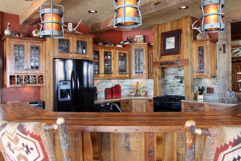 Example of a large mountain style u-shaped light wood floor eat-in kitchen design with flat-panel cabinets, light wood cabinets, granite countertops, beige backsplash, stone tile backsplash, black appliances and no island