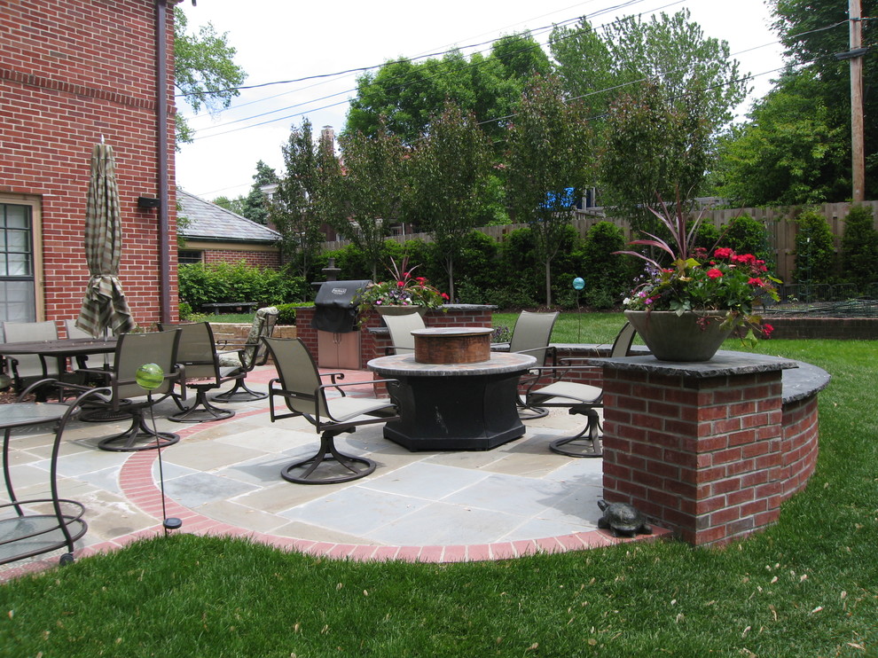 This is an example of a mid-sized traditional backyard partial sun formal garden for summer in Omaha with natural stone pavers and a fire feature.