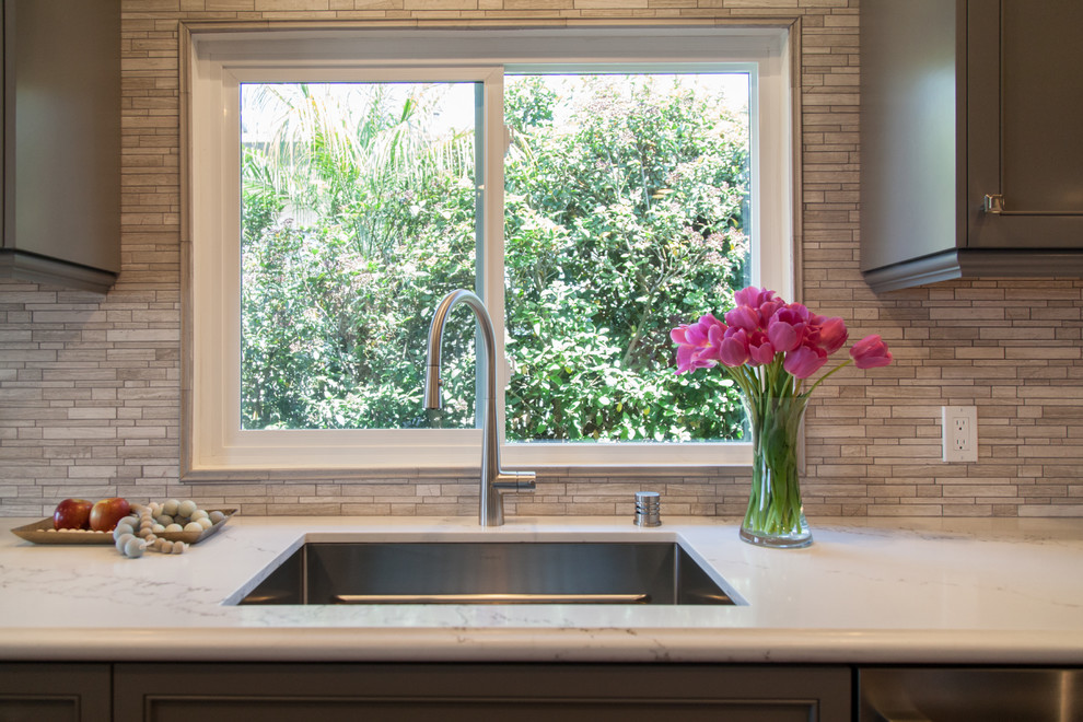 Mid-sized transitional l-shaped dark wood floor eat-in kitchen photo in Orange County with an undermount sink, shaker cabinets, gray cabinets, solid surface countertops, beige backsplash, matchstick tile backsplash, stainless steel appliances and a peninsula