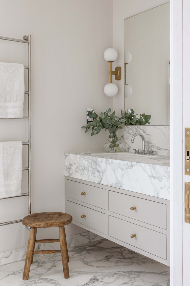 Inspiration for a mid-sized modern master bathroom in London with flat-panel cabinets, grey cabinets, a wall-mount toilet, gray tile, marble, grey walls, marble floors, an integrated sink, marble benchtops, white floor, a hinged shower door, white benchtops, a double vanity and a floating vanity.