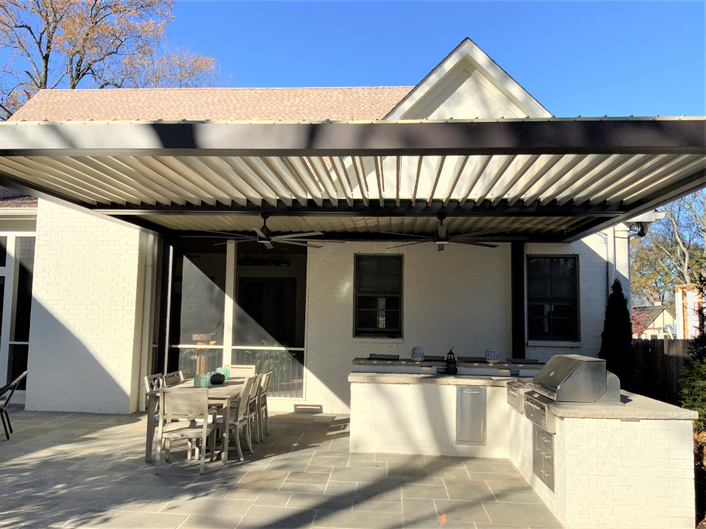Exemple d'une grande terrasse arrière tendance avec une cuisine d'été et des pavés en pierre naturelle.