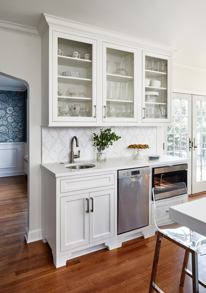 Inspiration for a mid-sized transitional u-shaped eat-in kitchen in DC Metro with a farmhouse sink, recessed-panel cabinets, blue cabinets, quartz benchtops, white splashback, marble splashback, panelled appliances, medium hardwood floors, with island, brown floor and white benchtop.