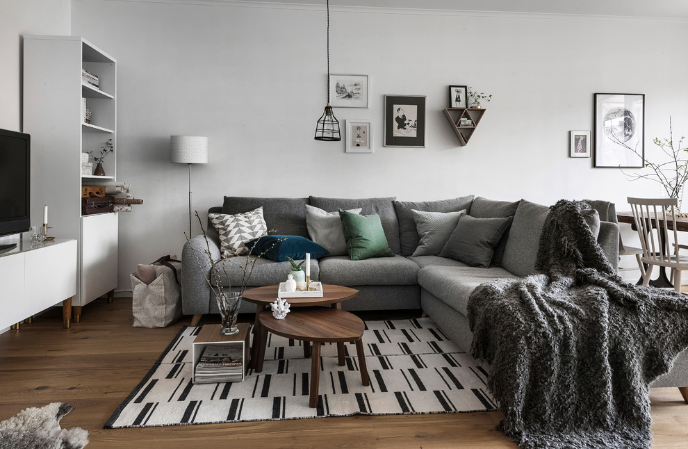 Inspiration for a scandinavian open concept family room in San Francisco with white walls, medium hardwood floors, a freestanding tv and brown floor.