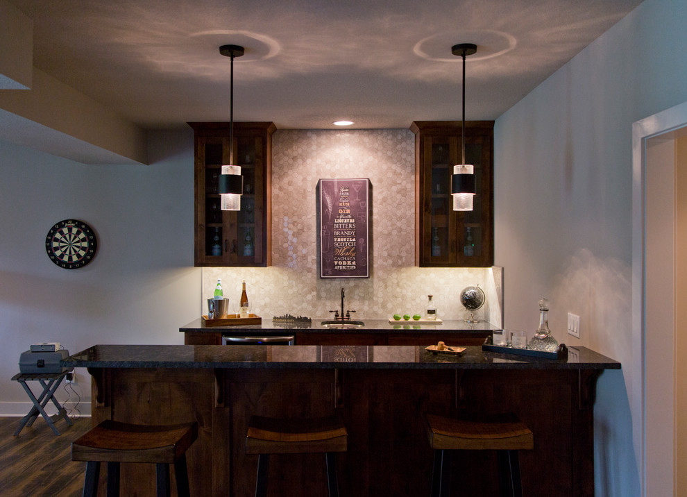 Photo of a mid-sized country galley seated home bar in Kansas City with an undermount sink, glass-front cabinets, dark wood cabinets, granite benchtops, grey splashback, dark hardwood floors and brown floor.