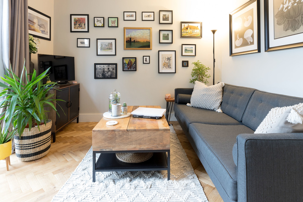 Photo of a medium sized eclectic enclosed living room in London with pink walls, medium hardwood flooring, a standard fireplace, a brick fireplace surround, a freestanding tv and brown floors.