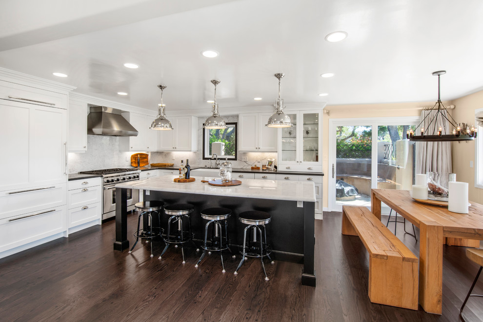 Mid-sized beach style l-shaped eat-in kitchen in San Francisco with a farmhouse sink, shaker cabinets, black cabinets, marble benchtops, grey splashback, marble splashback, panelled appliances, dark hardwood floors, with island, brown floor and multi-coloured benchtop.