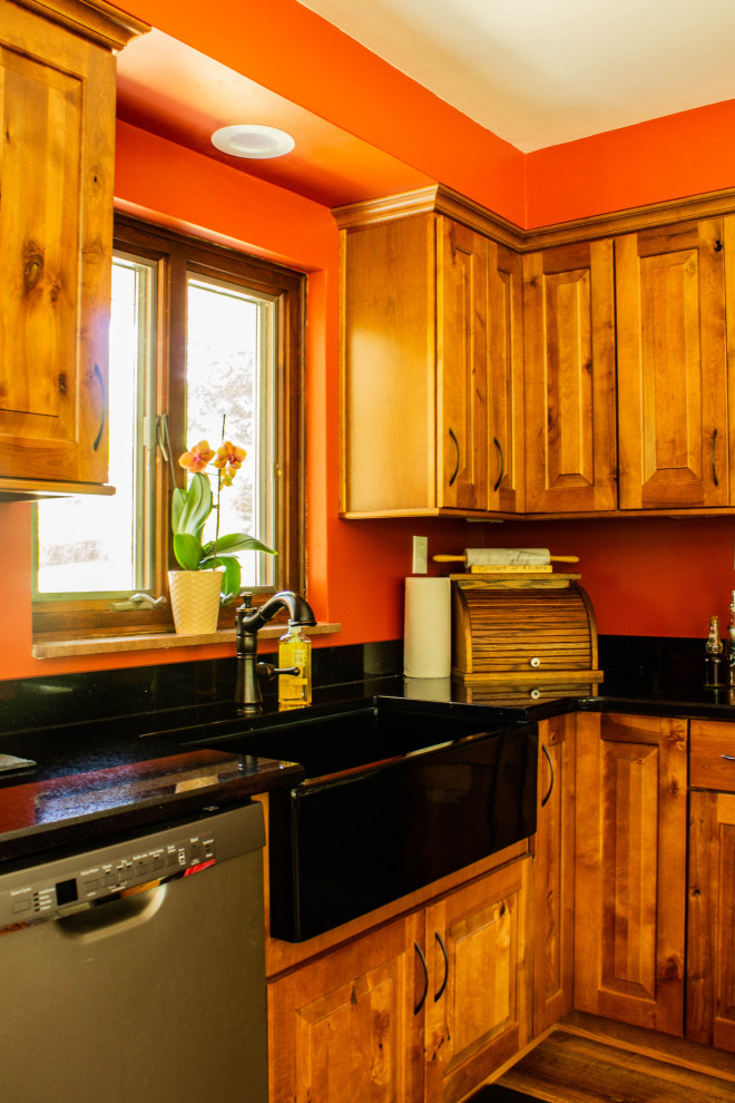 Open concept kitchen - large rustic u-shaped medium tone wood floor and brown floor open concept kitchen idea with a farmhouse sink, raised-panel cabinets, medium tone wood cabinets, quartz countertops, stainless steel appliances, an island and black countertops