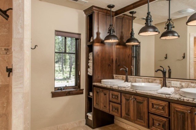 This is an example of a large country master bathroom in Portland with raised-panel cabinets, dark wood cabinets, brown tile, travertine, beige walls, travertine floors, a vessel sink, granite benchtops and beige floor.