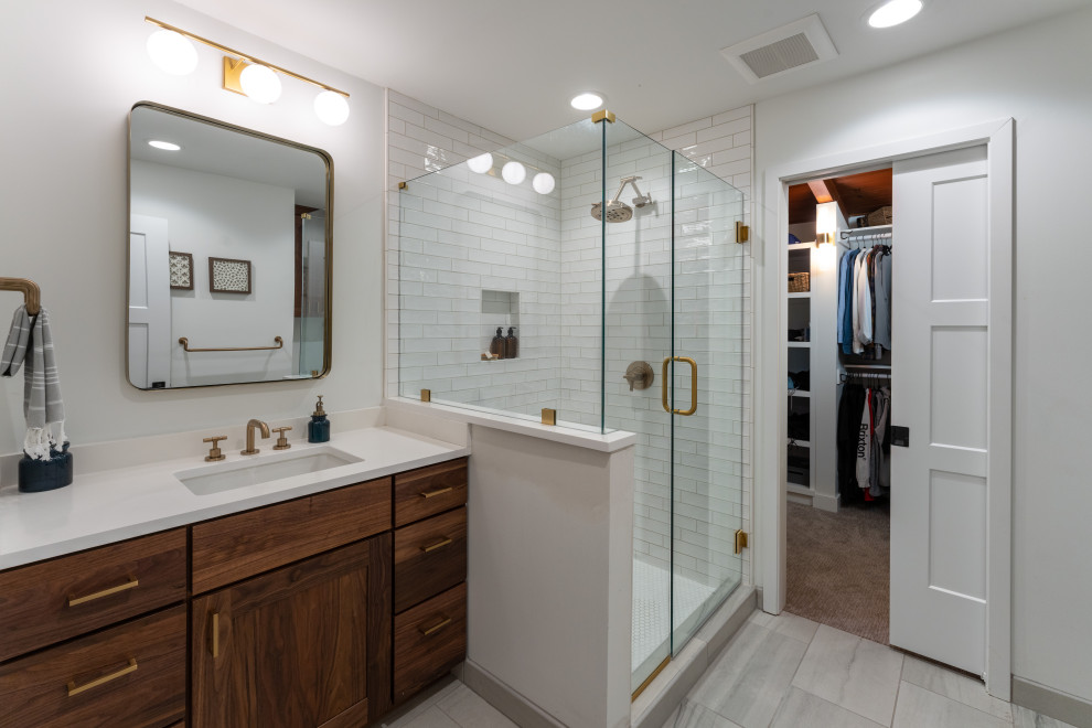 Example of a 1960s master white tile and ceramic tile marble floor, gray floor and double-sink corner shower design in Kansas City with recessed-panel cabinets, medium tone wood cabinets, white walls, an undermount sink, quartz countertops, a hinged shower door, white countertops and a built-in vanity
