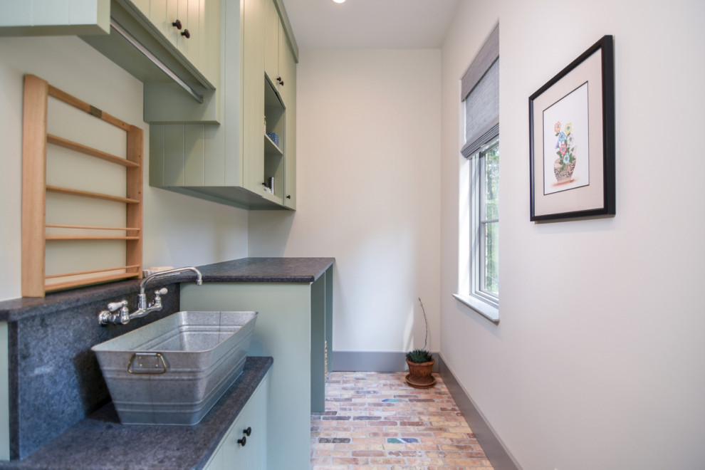 Design ideas for a mid-sized mediterranean single-wall dedicated laundry room in Other with a single-bowl sink, beaded inset cabinets, green cabinets, solid surface benchtops, white walls, brick floors, a concealed washer and dryer, multi-coloured floor and green benchtop.