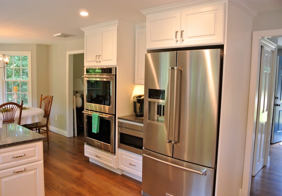 Transitional light wood floor eat-in kitchen photo in Boston with an undermount sink, raised-panel cabinets, white cabinets, granite countertops, white backsplash, subway tile backsplash and stainless steel appliances