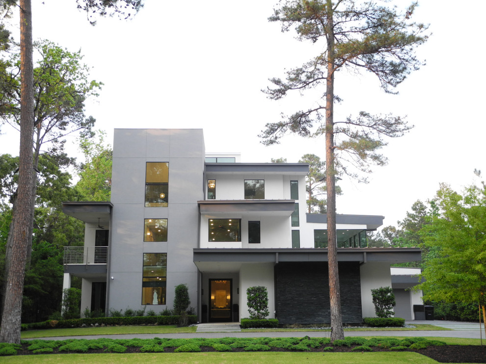 Geräumiges, Dreistöckiges Modernes Einfamilienhaus mit Putzfassade, weißer Fassadenfarbe, Flachdach, Blechdach und weißem Dach in Houston