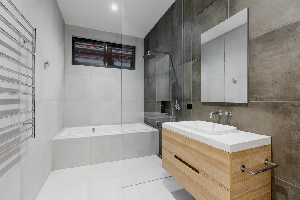Photo of a mid-sized contemporary master bathroom in Melbourne with an open shower, a drop-in sink, light wood cabinets, a corner tub, cement tile, grey walls, marble floors, granite benchtops, white floor and an open shower.