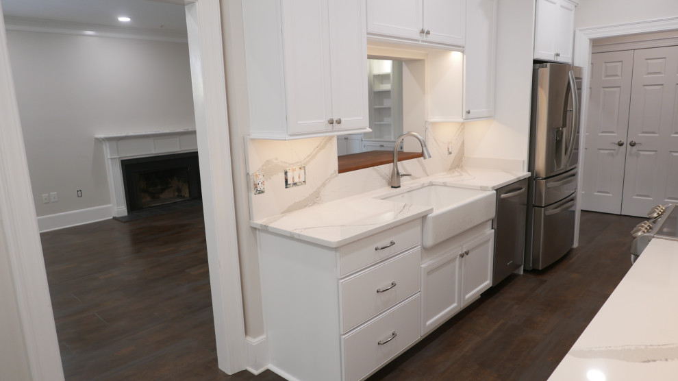 Mid-sized transitional galley laminate floor and multicolored floor eat-in kitchen photo with a farmhouse sink, shaker cabinets, white cabinets, quartz countertops, white backsplash, quartz backsplash, stainless steel appliances and white countertops
