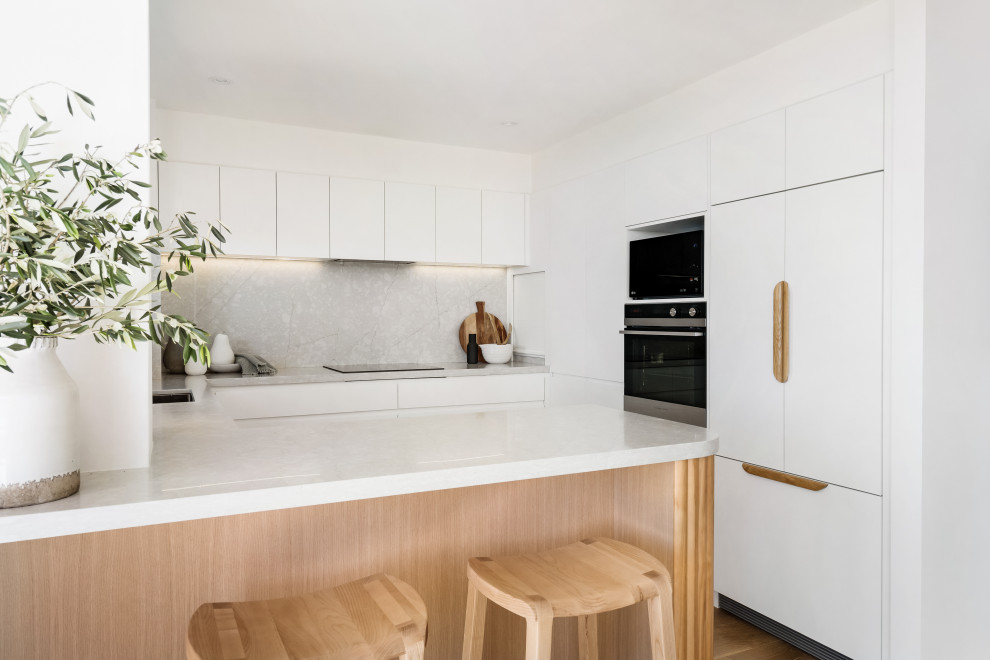 This is an example of a small contemporary u-shaped kitchen in Sydney with engineered stone countertops and engineered quartz splashback.