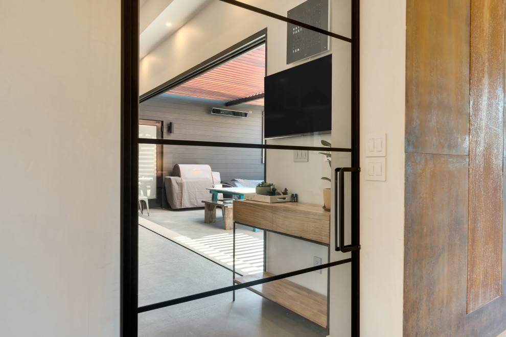 Modern inredning av ett mellanstort separat vardagsrum, med bruna väggar, betonggolv, en dubbelsidig öppen spis, en spiselkrans i metall, en väggmonterad TV och grått golv