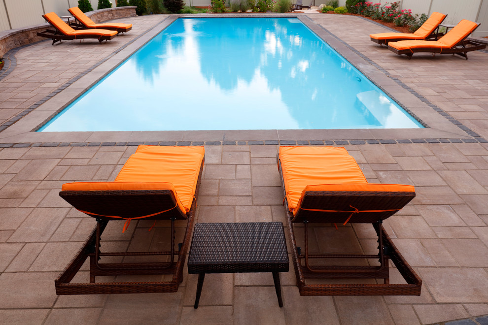 Inspiration for a large traditional backyard rectangular lap pool in Boston with concrete pavers.