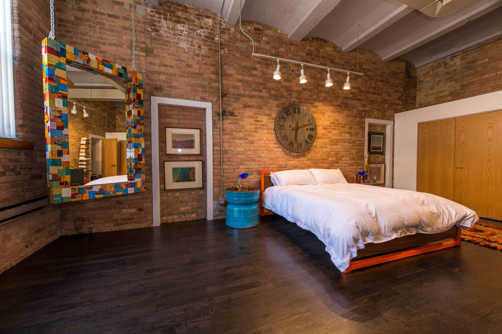 Industrial master bedroom in Chicago with dark hardwood floors.