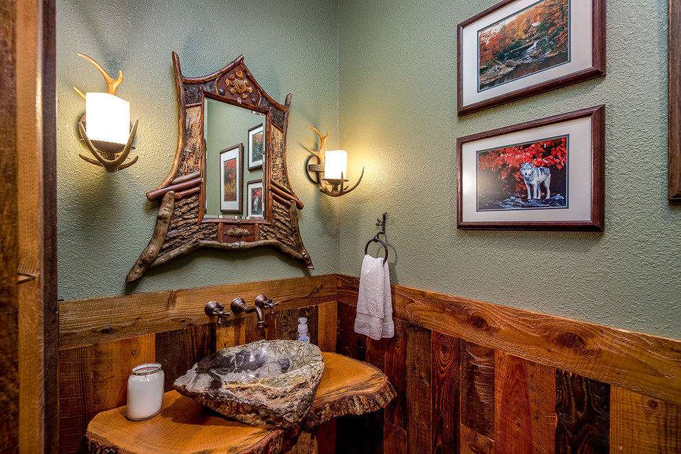 Example of a mid-sized mountain style dark wood floor and brown floor powder room design with a two-piece toilet, green walls, a vessel sink, wood countertops and brown countertops